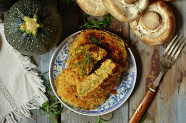 Cutlets with courgette and mushrooms on a rustic saucer on a wooden background