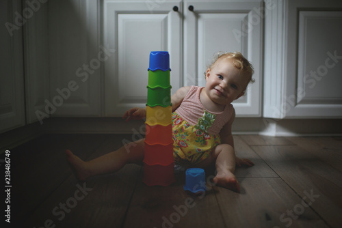 Portrait of girl with colorful toys sitting on hardwood floor at home