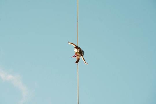 Low angle view of man slacklining against clear blue sky during sunny day