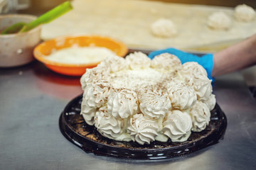 Gloved hands in process of making meringue cake and desserts. Production of confectionery