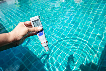 Digital water testing in girl hand over blue swimming pool water background, water analysis technology