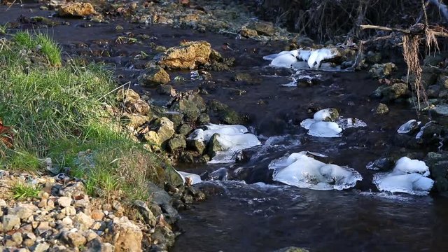 Beautiful photo of water flowing down a rocky, icy creek with audio on a cold clear winter day.