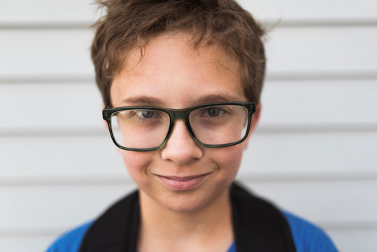 Close-up portrait of boy wearing eyeglasses while standing by wall