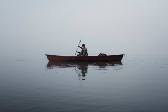 Woman rowing boat on river at Algonquin Provincial Park during foggy weather