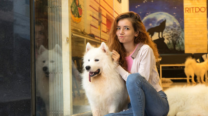 Girl with a big fluffy white dog, hugging and playing with dog