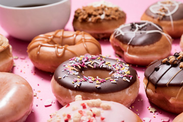 High angle view of various donuts with coffee arranged on pink background
