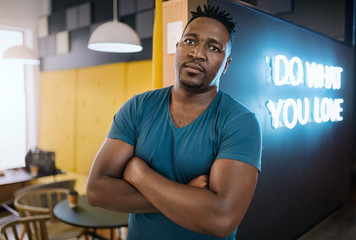 Confident african american man standing with his arms crossed in a trendy cafe