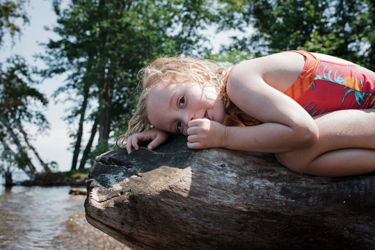 Portrait of girl sucking thumb while lying on log