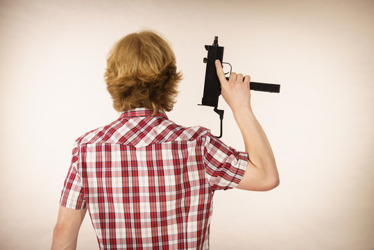 Man standing backwards holding gun