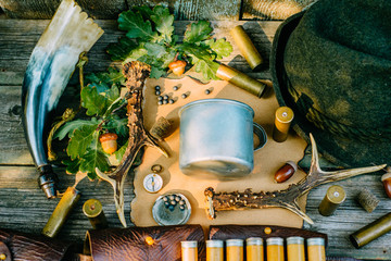 Aluminum mug on vintage paper among hunting and tourist equipment on wooden background