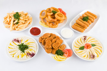 French Fries, Onion Rings, Mozzarella Cheese Sticks, Chicken Nuggets, Hummus and Baba ghanoush on the  table