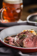 Sliced Beef tenderloin roasted steak potatoes rosemary and draft beer