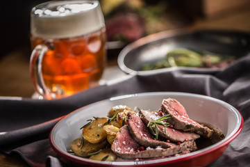 Sliced Beef tenderloin roasted steak potatoes rosemary and draft beer