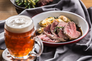 Sliced Beef tenderloin roasted steak potatoes rosemary and draft beer