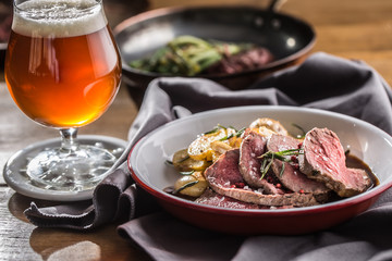 Sliced Beef tenderloin roasted steak potatoes rosemary and draft beer