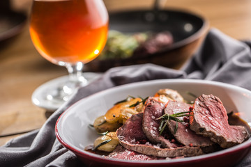 Sliced Beef tenderloin roasted steak potatoes rosemary and draft beer