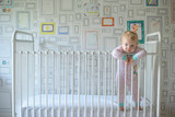 Portrait of toddler leaning on crib at home