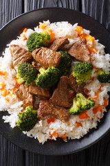 Asian beef with broccoli served with rice and persimmon close-up on a plate. Vertical top view
