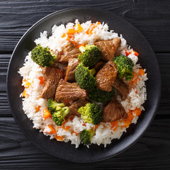 Roasted beef with broccoli with rice and persimmon side dish close-up on a plate. top view