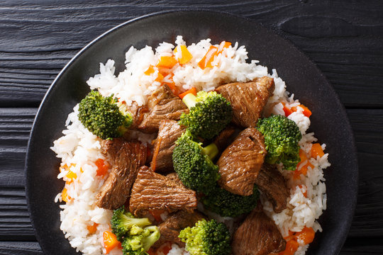 Stir-fried beef broccoli with rice and persimmon side dish close-up on a plate. horizontal top view