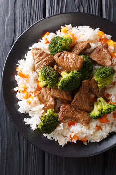 Stir-fried beef broccoli with rice and persimmon side dish close-up on a plate. Vertical top view