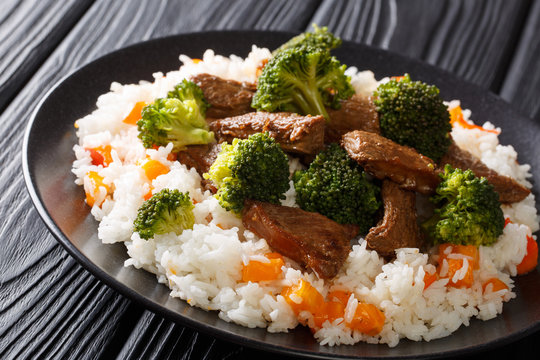 Delicious grilled beef with broccoli served with rice and persimmon close-up on a plate. horizontal