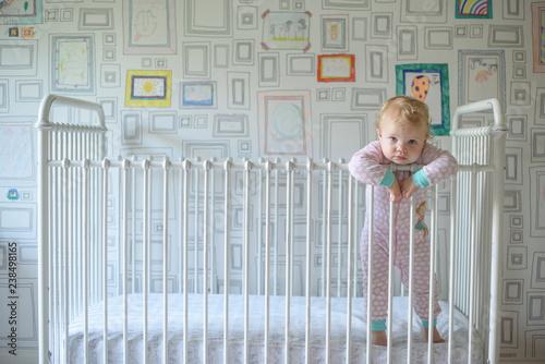 Portrait of toddler leaning on crib at home