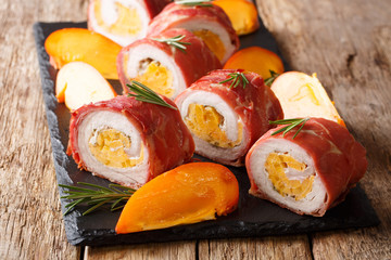 Christmas pork roll baked in prosciutto and stuffed with fresh persimmon and cheese close-up. horizontal