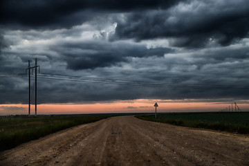 Road, field and dark clouds in the sky