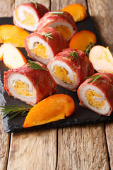 Pork tenderloin baked in prosciutto and stuffed with persimmon and cheese close-up. vertical