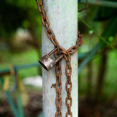Closeup Closeup picture of rusted lock and chain on the steel column with blurred bokeh bpicture of rusted lock and chain on the steel column with blurred bokeh background. Love and commitment concept