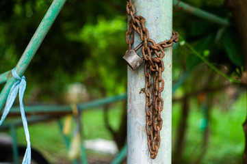 Closeup picture of rusted lock and chain on the steel column with blurred bokeh background. Love and commitment concept.