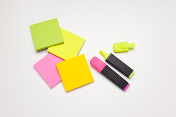 Sticky notes with markers, colored pens, paper clips laying on a table