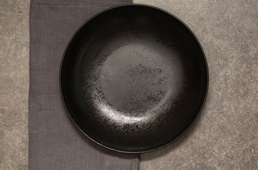 Black plate, Cutlery and napkin on grey stone table. 