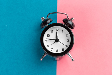 Vintage black alarm clock on a color block background