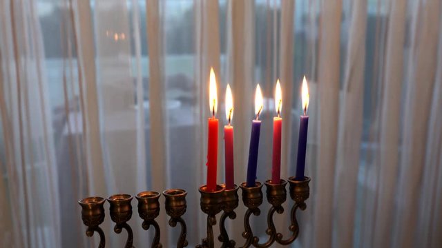 Five candles in hanukkiah are burning on light curtain background on the fourth day of the Jewish holiday Hanukkah. Selective focus, 4k