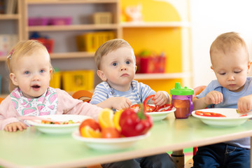 children toddlers eating healthy food in nursery or kindergarten