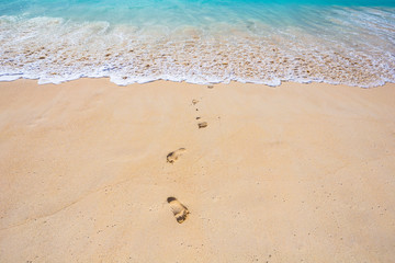 Footprints on a sand at the beach on sunny day
