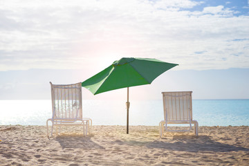 White chairs and umbrella at a beach at sunset time