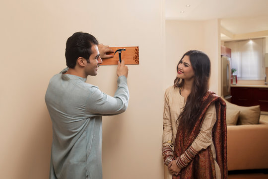 Young couple newlywed in traditional dress placing name plate to home	