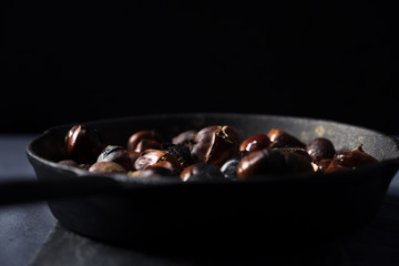 Fried chestnuts in rustic pan close up
