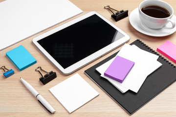 Digital tablet with notepad, supplies and coffee cup on desktop.
