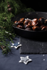 Fried chestnuts with sea salt in rustic pan served on blue table cloth