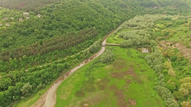 Amazing aerial view of mountain forest and river valley with small bridge