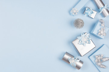 Winter festive background for advertising and design - set of blue and silver metallic gift boxes with ribbons on soft light pastel blue color backdrop, copy space.