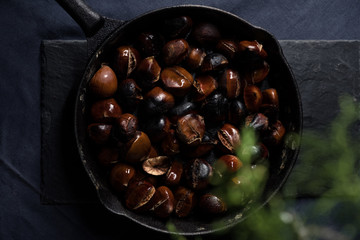 Fried chestnuts served on blue table cloth under Christmas decorated thuja