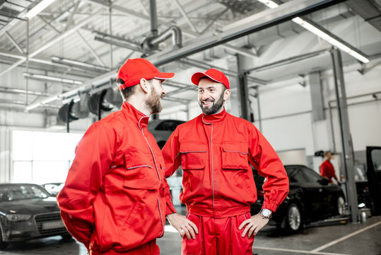 Two Auto Mechanics In Red Uniform Talking Together During The Break At The Car Service