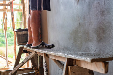 Showing legs of a man standing on the Wood bench while working in a construction site