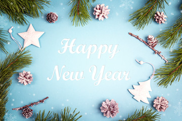 New year greeting message with fir branches and white decorations on the blue background.