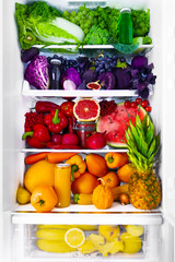 Fresh organic healthy raw antioxidant violet, red, green, orange and yellow food, vegetables, fruits and juices in vegan vegetarian opened full fridge of vitamins. Healthy eating diet and lifestyle.